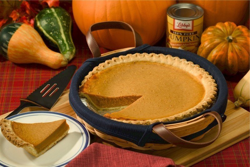 A slice of pumpkin pie next to the whole pie