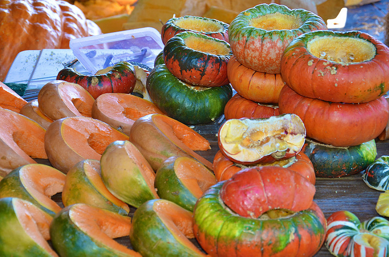 Large pumpkin segments placed to the left of some hollowed out whole pumpkins